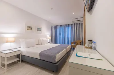 a hotel room with a bed with a desk and a window at Hotel Baltum in Albufeira