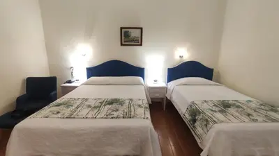 two beds in a small room with blue chairs at Aeromar Beach Hotel in Faro