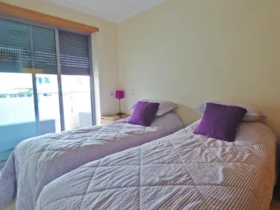 a bedroom with two beds with purple pillows and a window at Apartamento Olhos D'Água in Albufeira