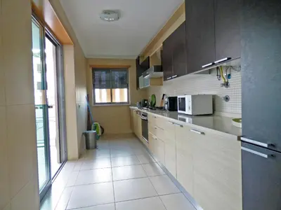 a kitchen with brown cabinets and a large window at Apartamento Olhos D'Água in Albufeira