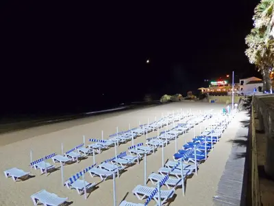 a bunch of chairs on a beach at night at Apartamento Olhos D'Água in Albufeira