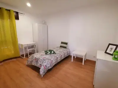 a small bedroom with a bed and two tables at Apartamento Penha in Faro