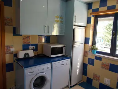 a kitchen with a washing machine and a microwave at T1 e T2 Marina Albufeira apartments in Albufeira