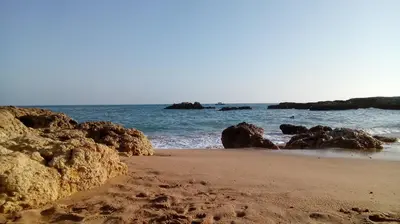 a sandy beach with rocks and the ocean at 5 Minutes Walk from the Beach in Albufeira