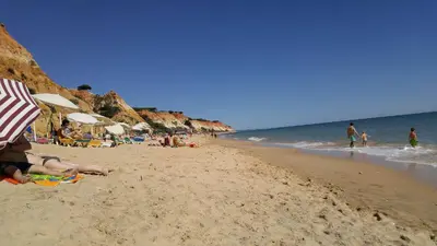 a group of people on a beach with umbrellas at Olhos de Água Apartment Albufeira in Albufeira