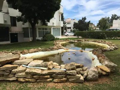a pond in a yard with rocks around it at Apartamento Vilamoura Marina in Vilamoura