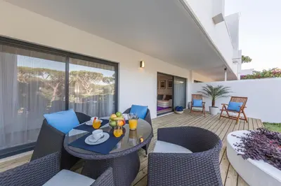 a patio with a table and chairs on a deck at NOA Apartment Quinta do Lago in Quinta do Lago
