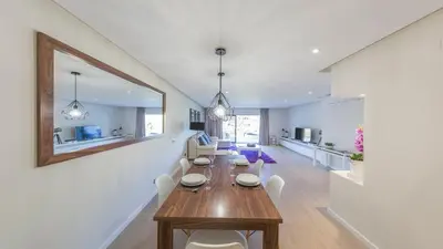 a dining room and living room with a table and chairs at NOA Apartment Quinta do Lago in Quinta do Lago