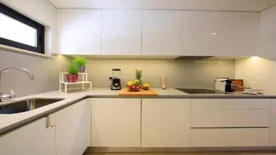 a kitchen with white cabinets and fruits on a cutting board at NOA Apartment Quinta do Lago in Quinta do Lago