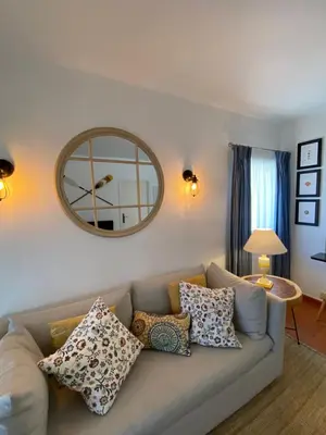 a living room with a couch with pillows and a mirror at Quinta do Lago Golf in Quinta do Lago