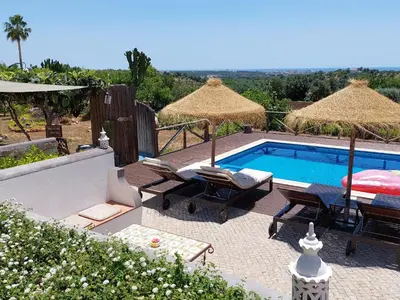 a swimming pool with chairs and umbrellas next to at Retiro da Janela in Boliqueime