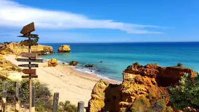 a beach with rocks and the ocean with a bunch of signs at São Rafael Golden Pearl Haven in Albufeira