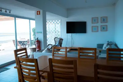 a dining room with a table and chairs and a television at Wax Hostel in Faro