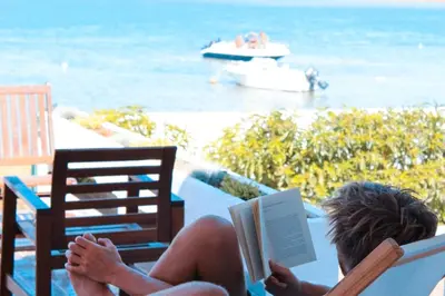 a woman sitting in a chair reading a book at Wax Hostel in Faro