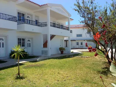 a large white house with a green yard at Jazzy Cool Apartment Near White Sand Beaches in Albufeira