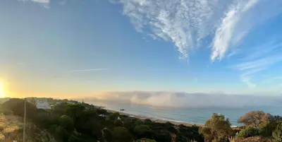 a view of a beach with a cloudy sky and the ocean at Golden Cliff House in Albufeira