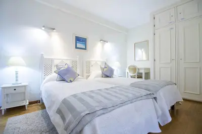 a white bedroom with two beds with blue pillows at Rubi in Vilamoura