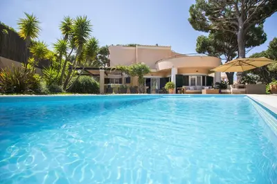 a swimming pool in front of a house at Rubi in Vilamoura