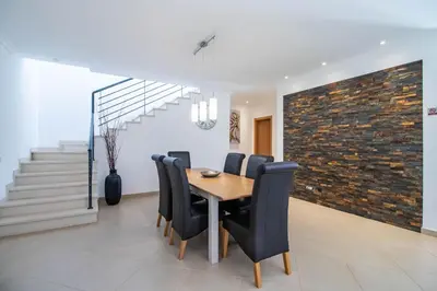 a dining room with a wooden table and black chairs at Casa no Sol in Loulé
