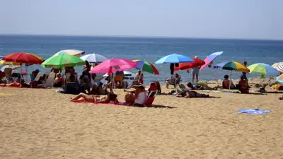 a group of people sitting on a beach with umbrellas at Alsol in Quarteira