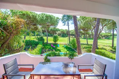 a patio with a table and chairs and a garden at Villa Beira Golf in Quarteira