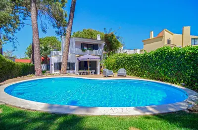 a yard with two chairs and a swimming pool at Villa Beira Golf in Quarteira