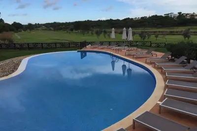 a palm tree in a pot on a balcony overlooking a golf course at Formosa Villas in Quinta do Lago