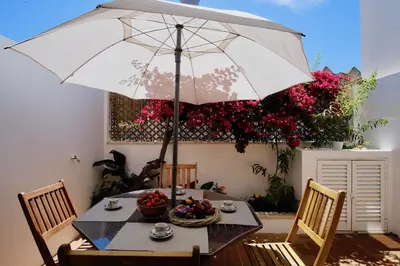 a table with an umbrella in a room with flowers at Casa da Avó in Faro