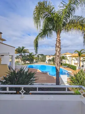 a palm tree in front of a swimming pool at Farm Village- Townhouse 2 mins from Old Town Albufeira in Albufeira