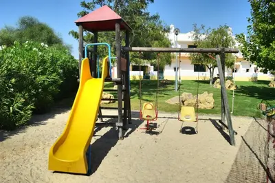a playground with a yellow slide and a swing at Townhouse 700m from Sao Rafael Beach in Albufeira