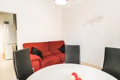 a living room with a table and a red couch at Akisol Quarteira Sunny in Quarteira