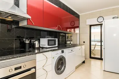 a kitchen with a washer and dryer and red cabinets at Akisol Quarteira Sunny in Quarteira