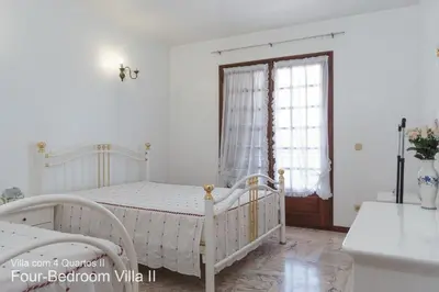 a white bedroom with a bed and a window at Akivillas Quarteira Rose in Quarteira