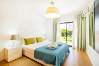 a bedroom with a bed and a large window at Villas Novochoro - Large Garden- Heatable Pool by DreamvillasAlbufeira in Albufeira