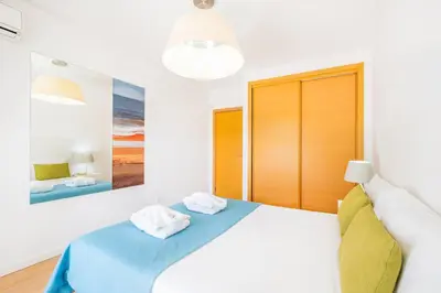 a white bedroom with a bed and a painting on the wall at Villas Novochoro - Large Garden- Heatable Pool by DreamvillasAlbufeira in Albufeira