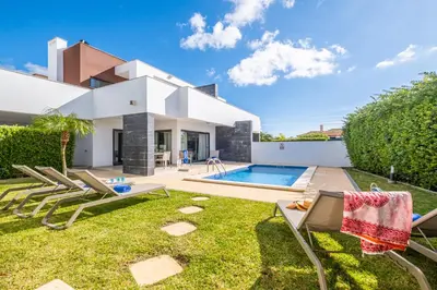 a backyard with chairs and a swimming pool at Villas Novochoro - Large Garden- Heatable Pool by DreamvillasAlbufeira in Albufeira