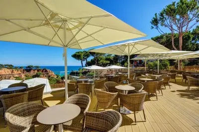 an outdoor restaurant with tables and chairs and umbrellas at 3HB Falésia Garden in Albufeira