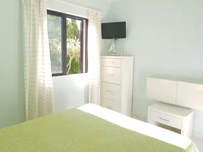 a white bedroom with a bed and a window at Algarve Apartment Falésia in Albufeira