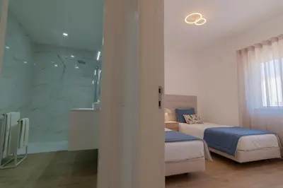 a bedroom with two beds and a glass shower at Apartments Salomé in Albufeira