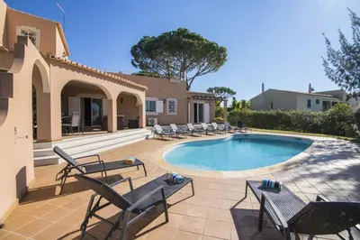 a swimming pool with chairs and a house at Villa Anita in Quarteira