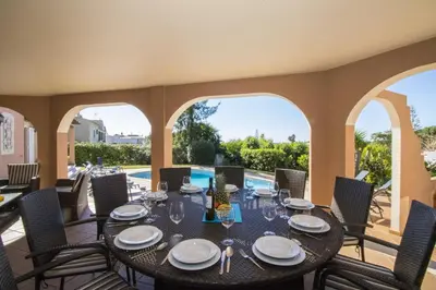 a dining room with a table and chairs on a patio at Villa Anita in Quarteira
