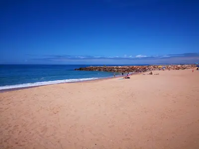 a group of people on a beach near the ocean at Mare Viva Beach Apartment in Quarteira