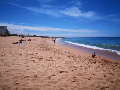 a group of people on a beach near the ocean at Mare Viva Beach Apartment in Quarteira