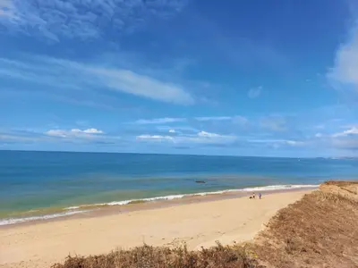 a beach with two people walking on the sand at Mare Viva Beach Apartment in Quarteira