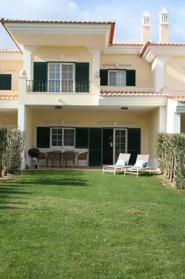 a house with two chairs and a table in the yard at Quinta Formosa - Villas in Quinta do Lago