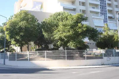 a fence with trees in front of a building at Albufeira Lovely new Apartment W/ Pool in Albufeira