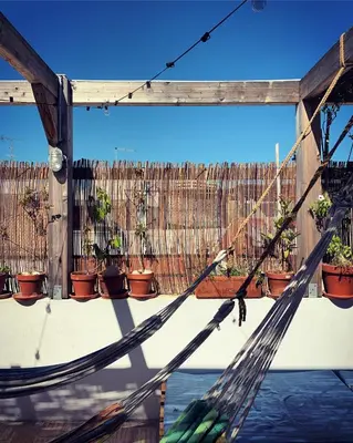 a hammock in front of a fence with potted plants at Casa da Madalena Backpackers Hostel in Faro