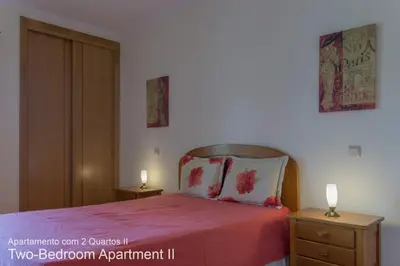 a bedroom with a bed with a pink blanket and two night stands at Akisol Vilamoura Nature in Vilamoura