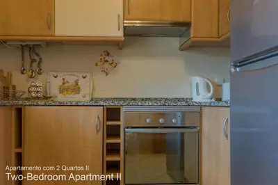 a kitchen with wooden cabinets and a stove top oven at Akisol Vilamoura Nature in Vilamoura