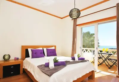 a bedroom with a bed with purple pillows and a balcony at Townhouse Mar 1 by Algarve Vacation in Albufeira